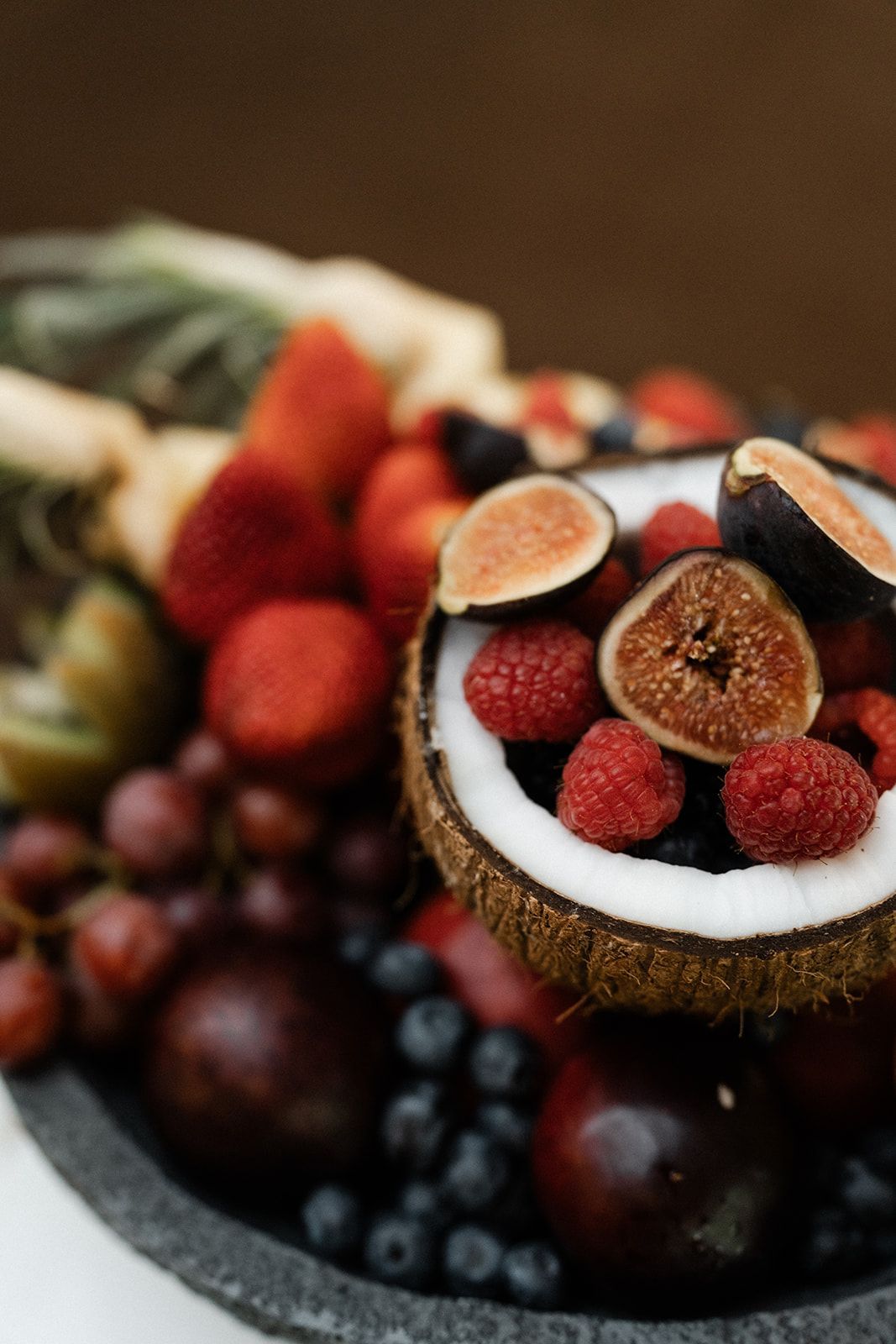 Fruit platter with coconut, figs, berries, grapes, and pineapple.
