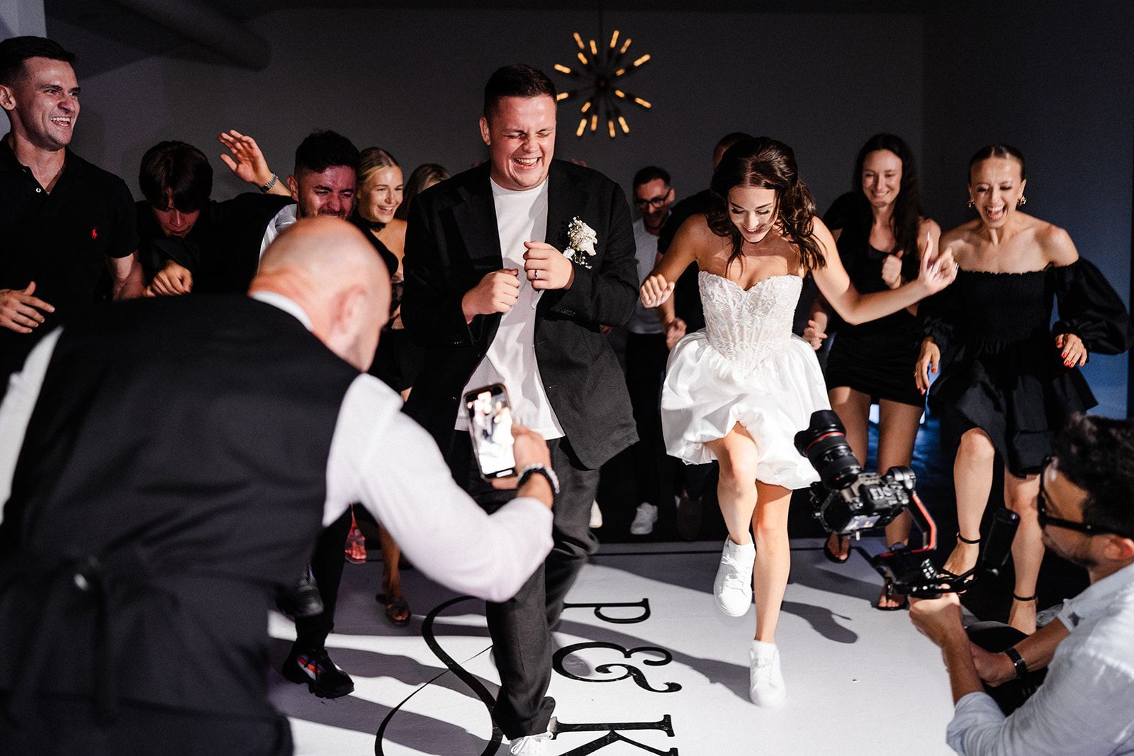 Wedding reception: Bride and groom joyfully dancing, surrounded by guests on dance floor.