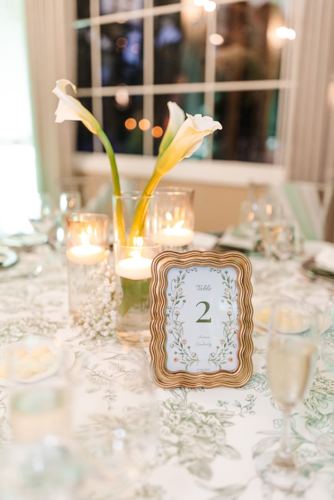 Table setting with calla lilies, floating candles, and framed table number 
