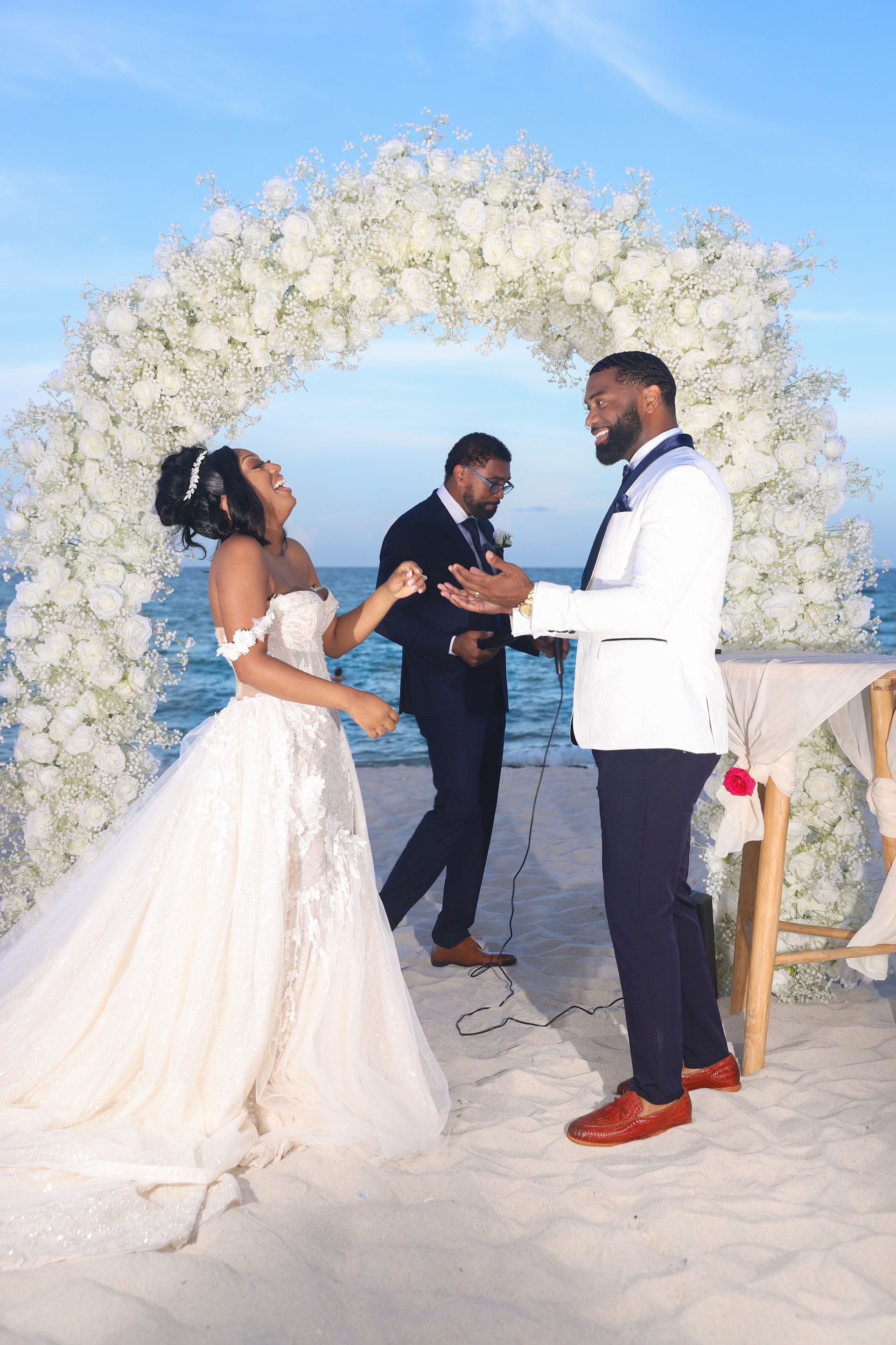 A bride and groom are dancing at their wedding ceremony on the beach.