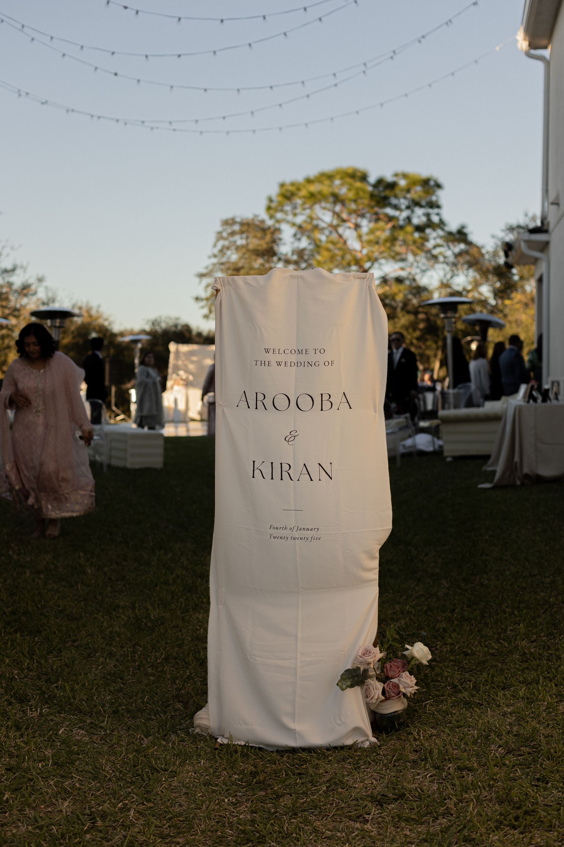 A white welcome sign draped in fabric, with the names 