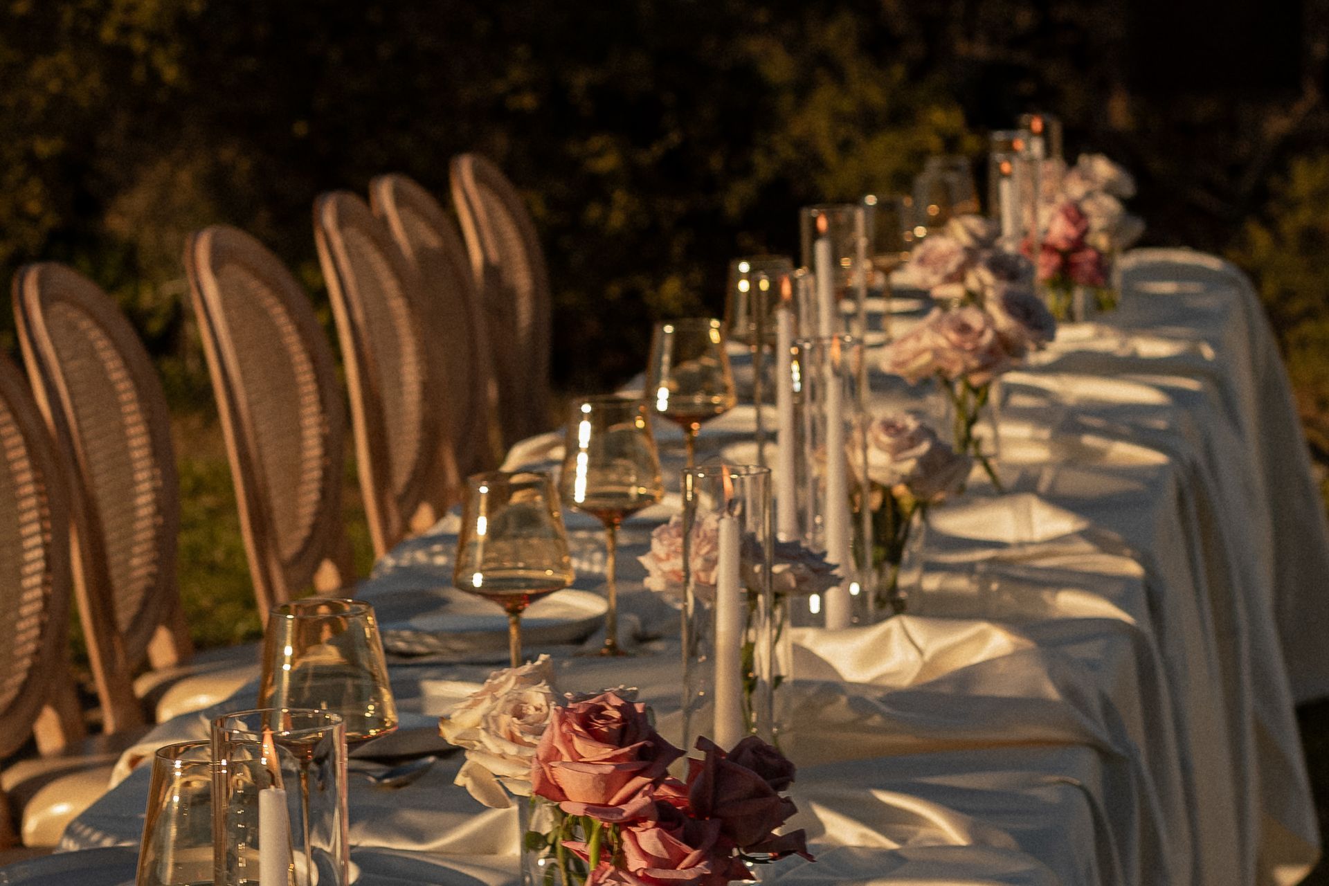Elegant table setting outdoors with flowers, candles, and champagne glasses.