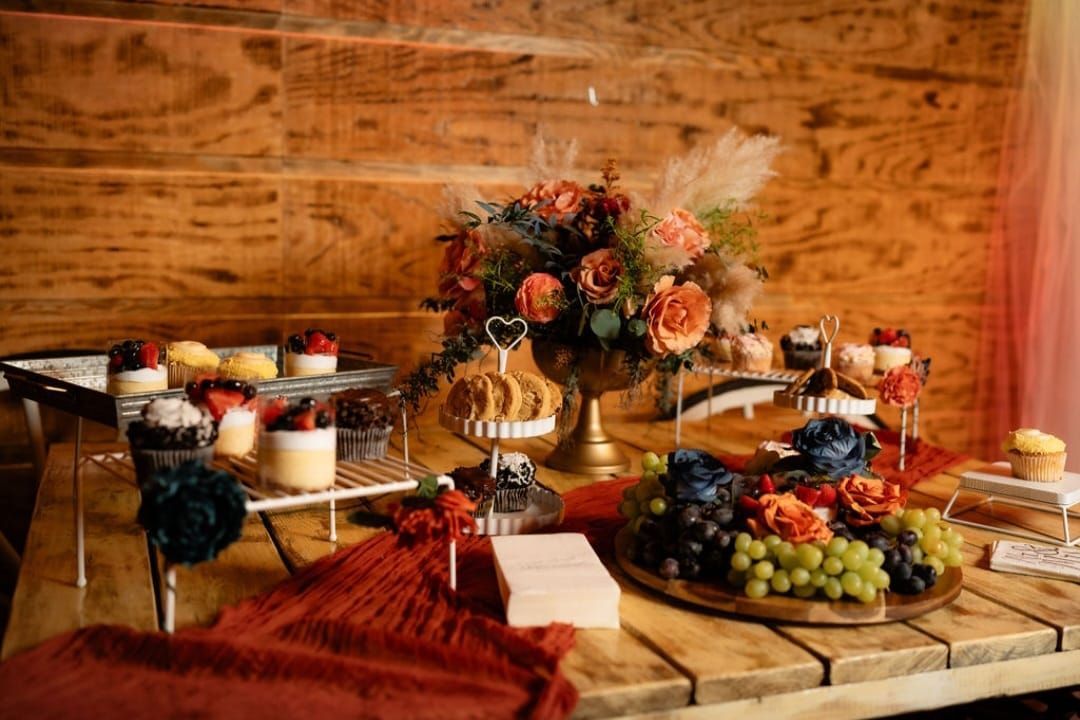 A wooden table topped with a variety of desserts and flowers.