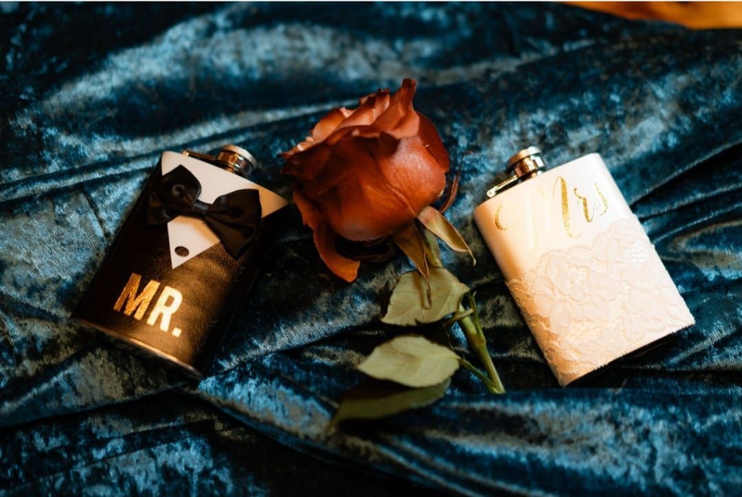 A couple of flasks sitting on top of a blue blanket next to a rose.
