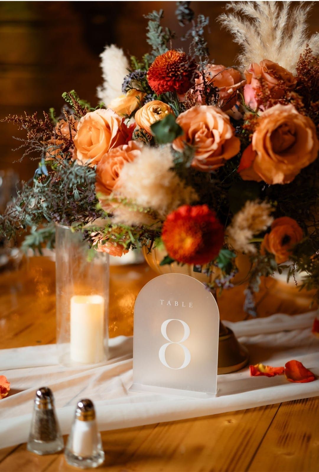 A table with a vase of flowers and a candle on it.