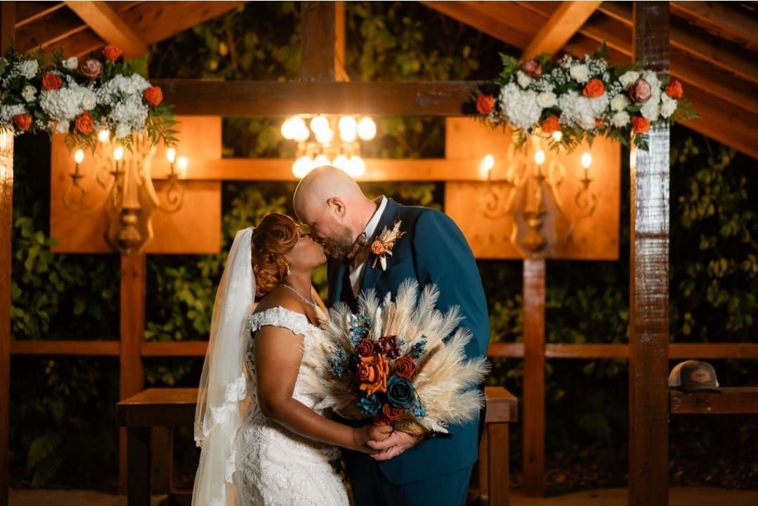 A bride and groom are kissing in a gazebo at their wedding.