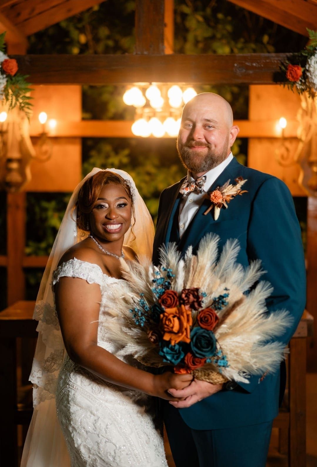 The bride and groom are posing for a picture at their wedding . the bride is holding a bouquet of flowers.