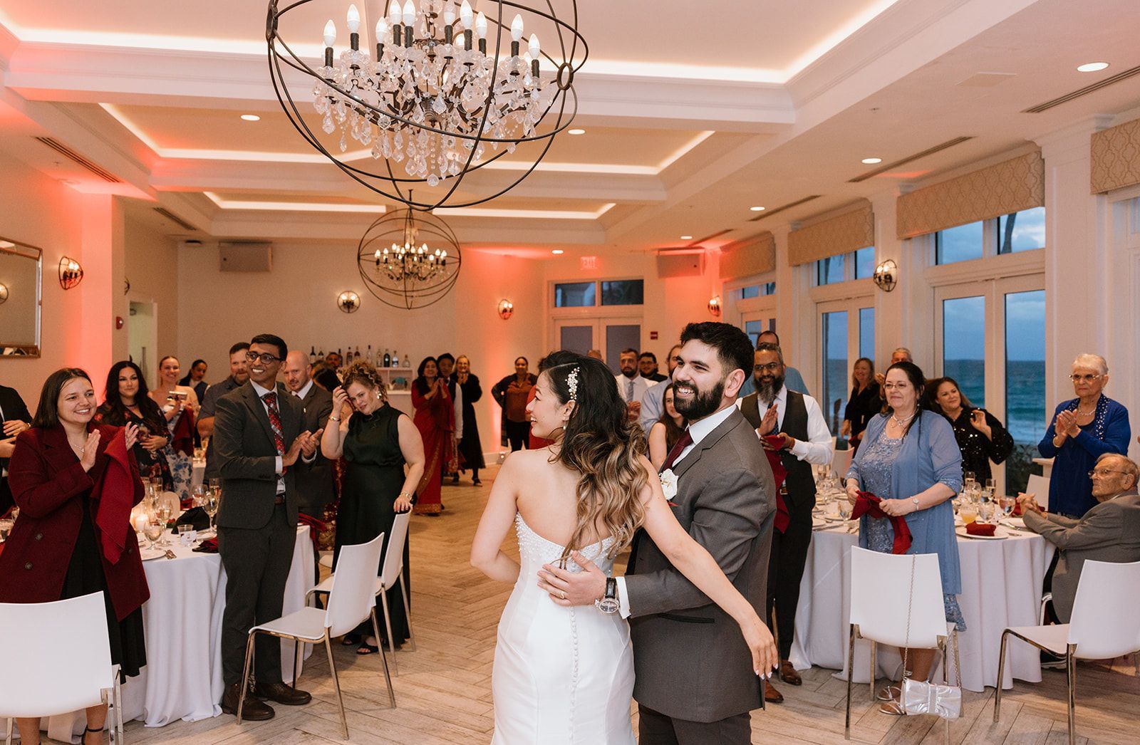 A bride and groom are dancing in a large room at their wedding reception.