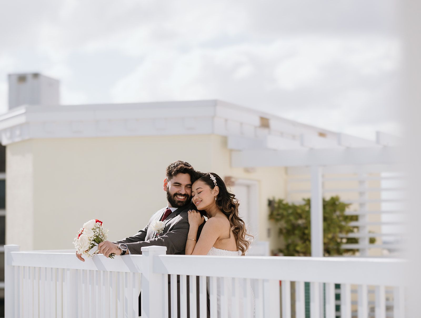 A bride and groom are posing for a picture on a balcony.