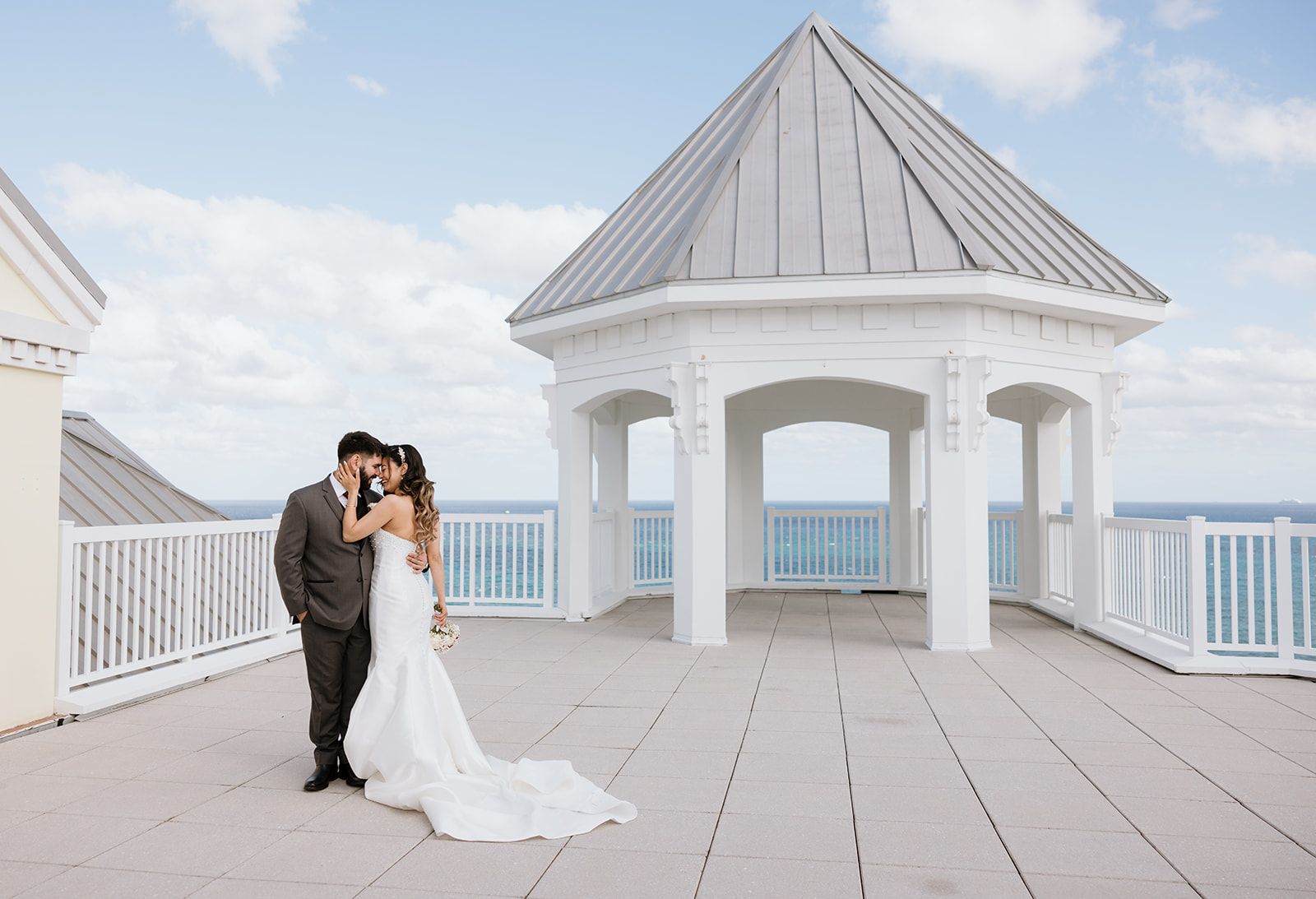 A bride and groom are posing for a picture in front of a gazebo.