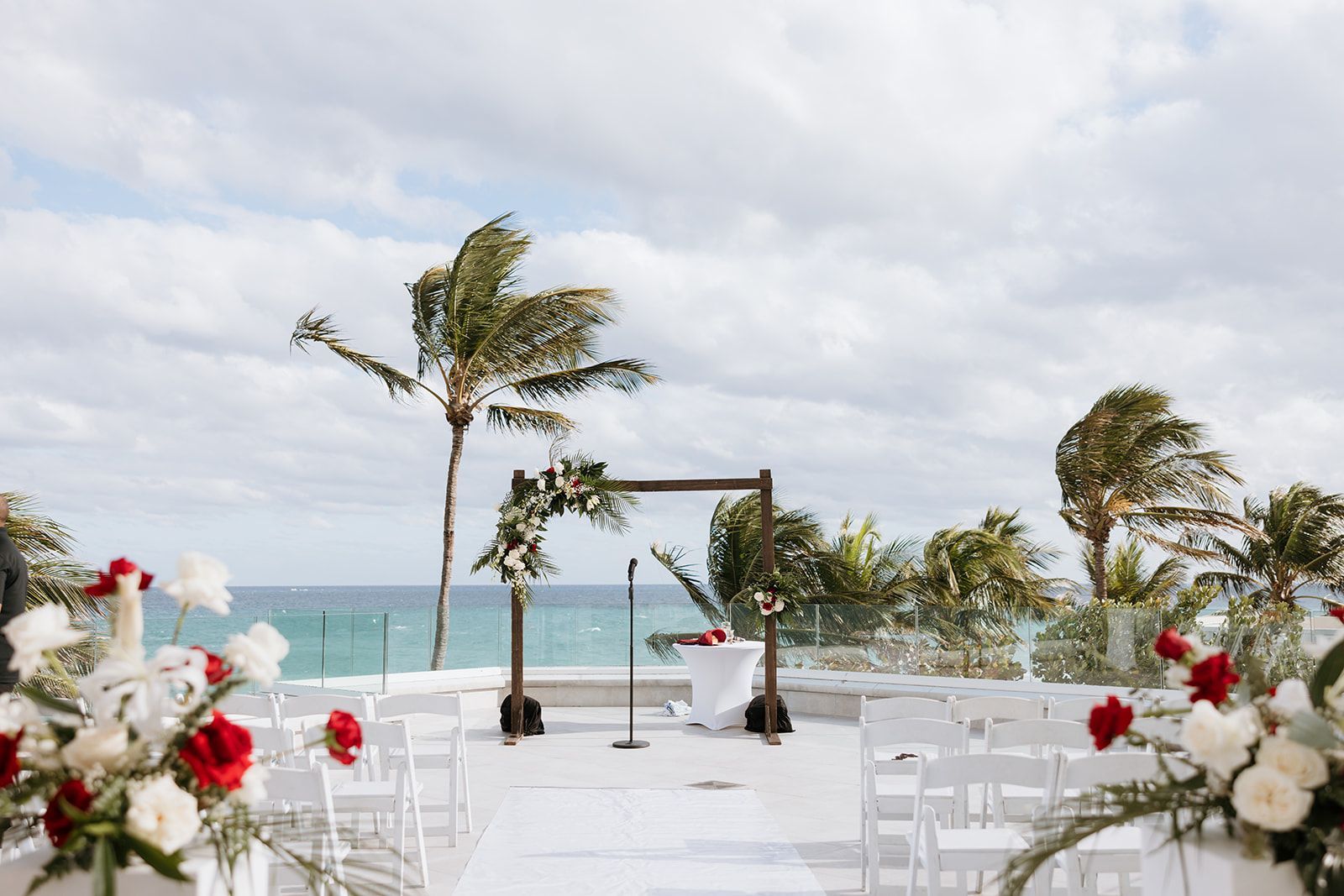 A wedding ceremony is taking place on a rooftop overlooking the ocean.