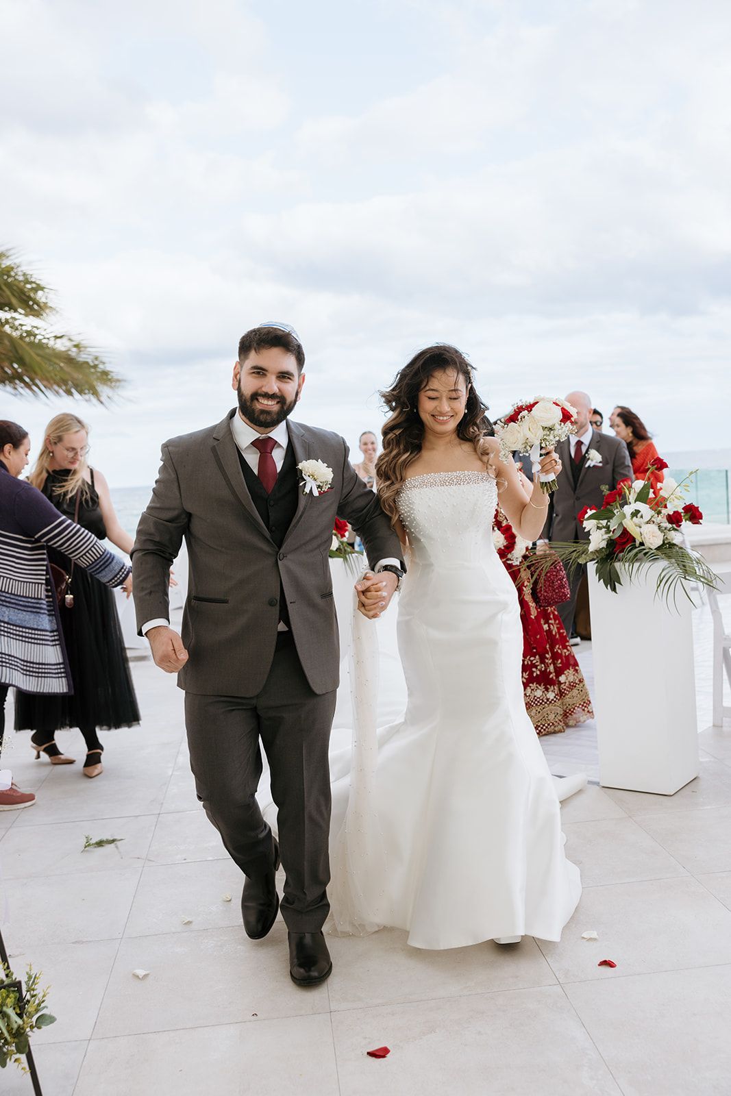 A bride and groom are walking down the aisle holding hands.