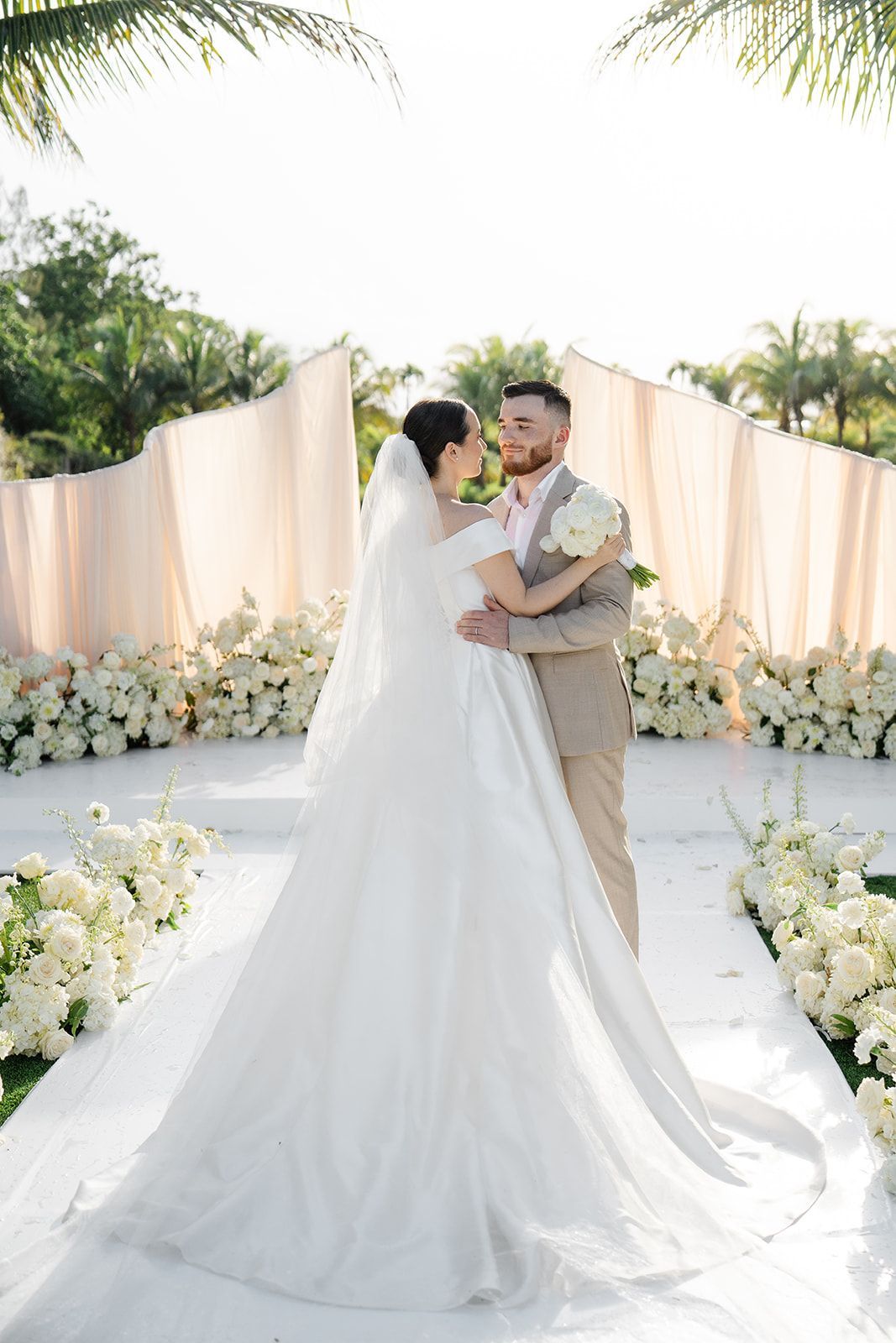 Miami wedding ceremony with wave arch and ivory cream romantic flowers