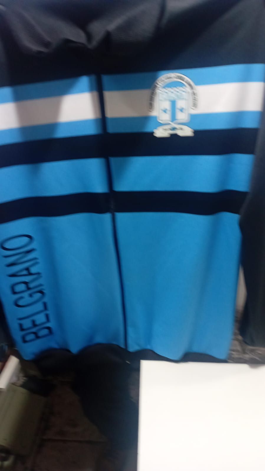 Chaqueta del equipo de fútbol Belgrano azul y negra con logo y rayas.
