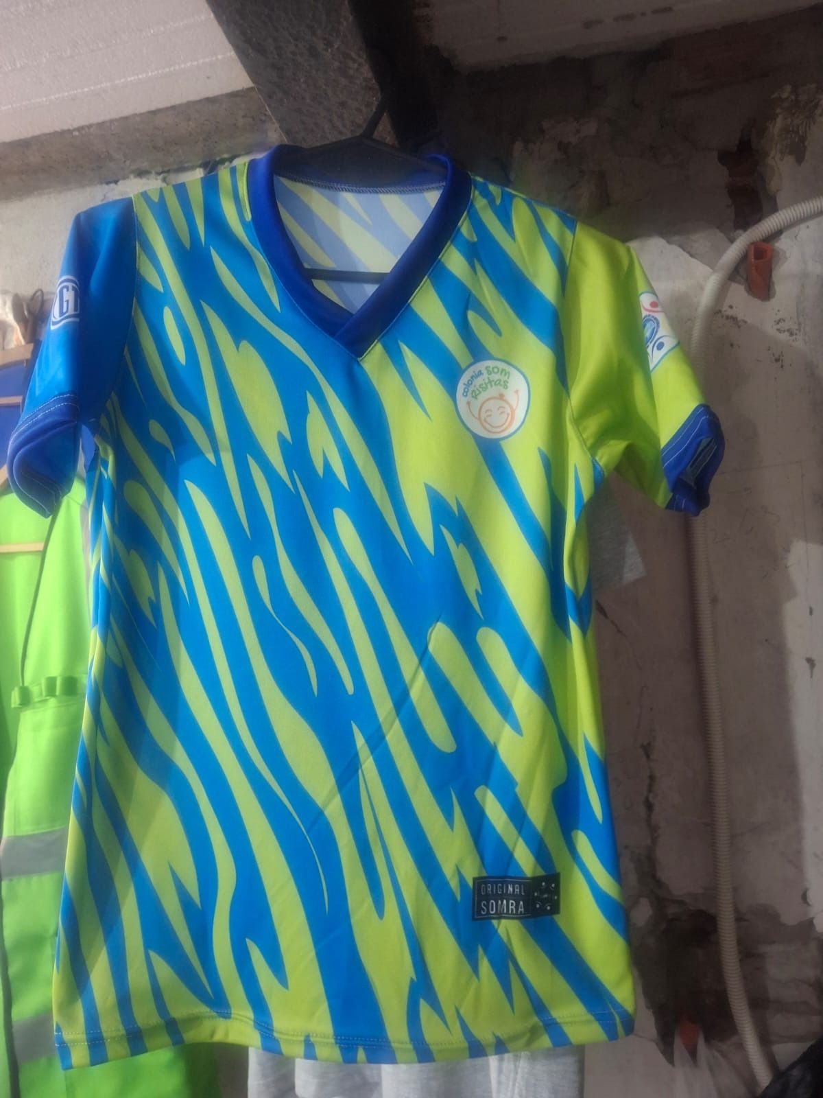 Camiseta de fútbol azul y amarilla con estampado de cebra colgada en una percha.