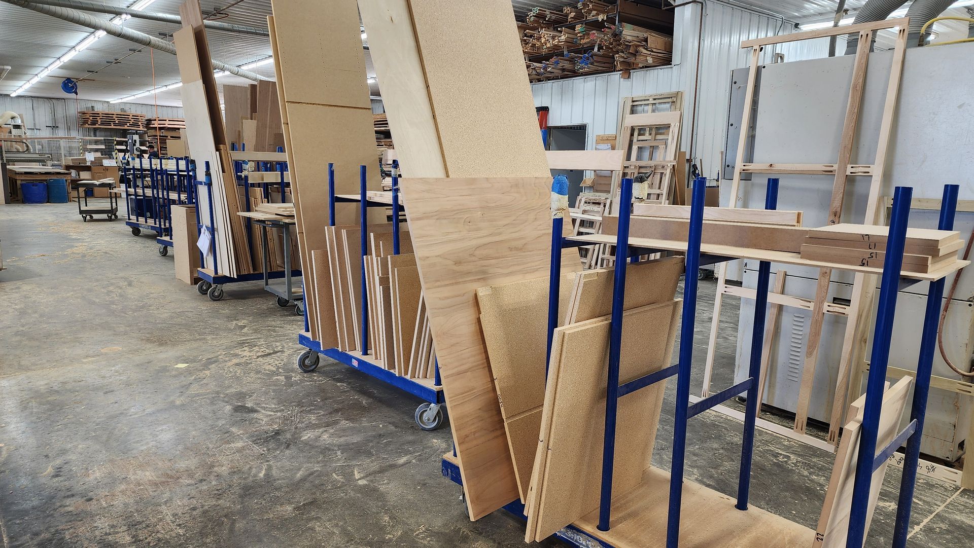 A warehouse filled with lots of wooden pieces on carts.