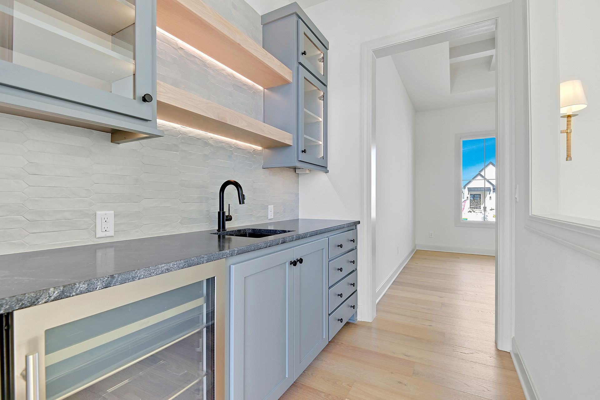 A kitchen with a sink , refrigerator , and a window.