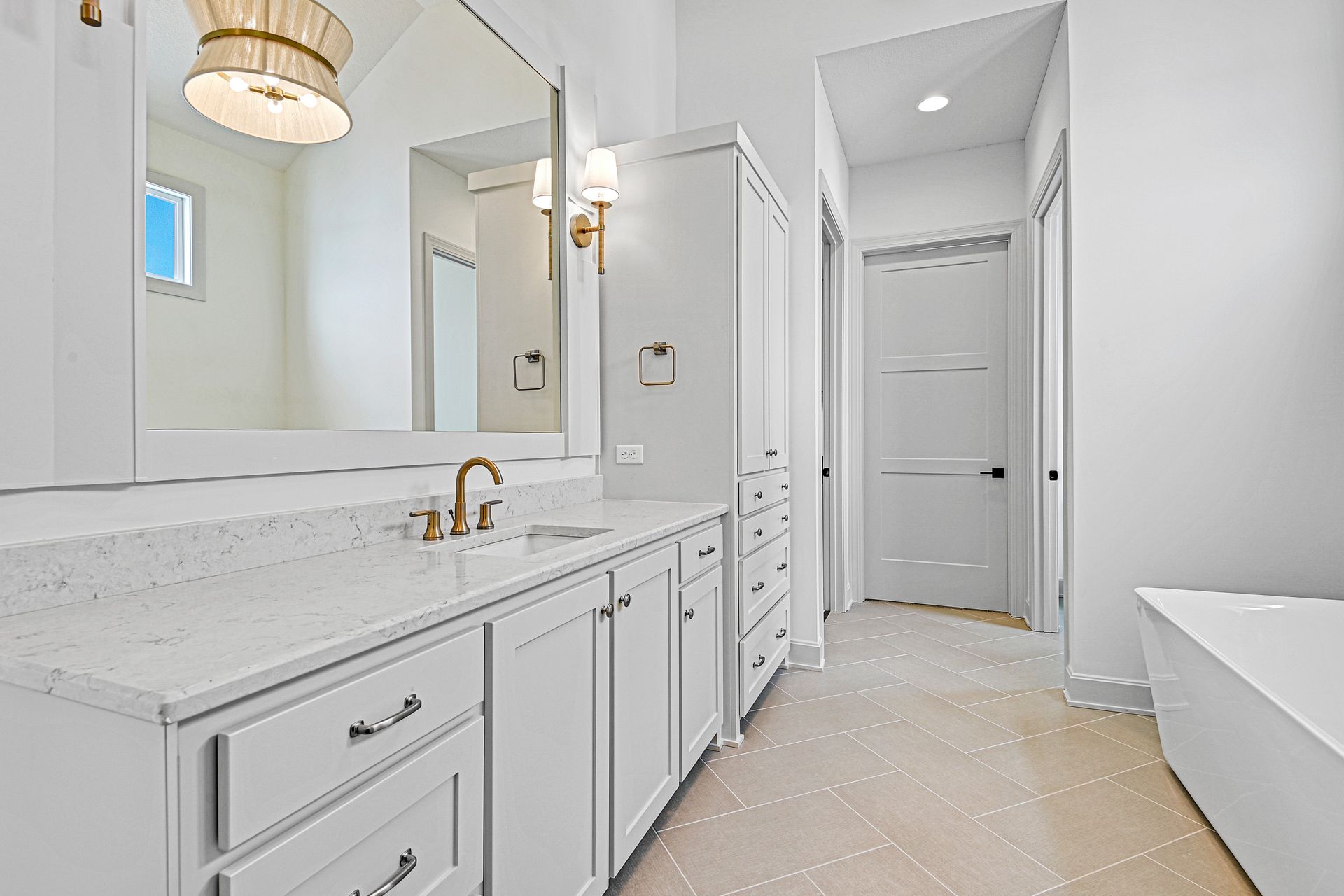A bathroom with a tub , sink , mirror and cabinets.