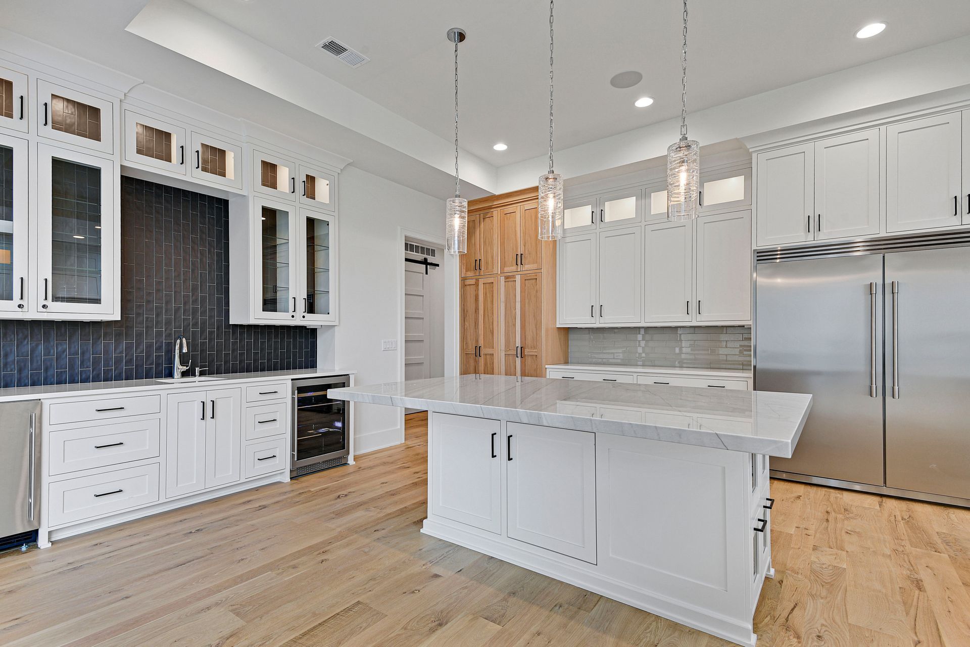 A kitchen with white cabinets , stainless steel appliances , and a large island.
