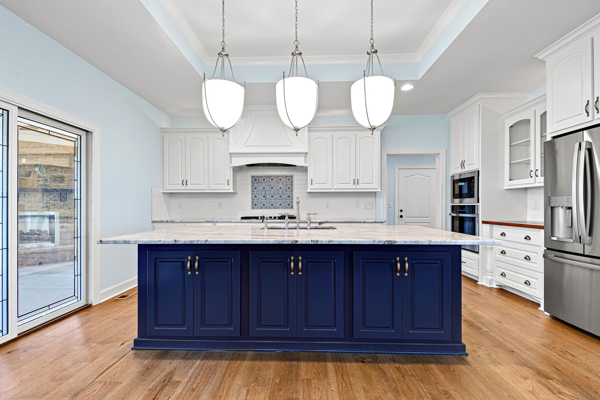 A kitchen with blue cabinets and white cabinets and a large island.