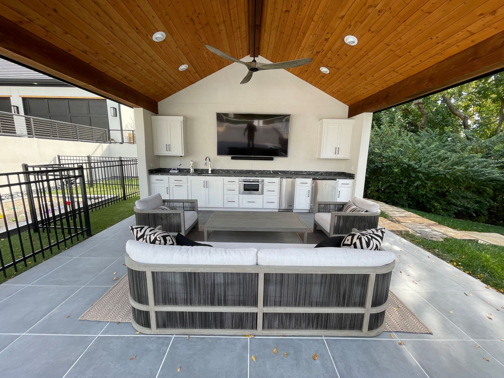 A living room with a couch , chairs , a television and a ceiling fan.