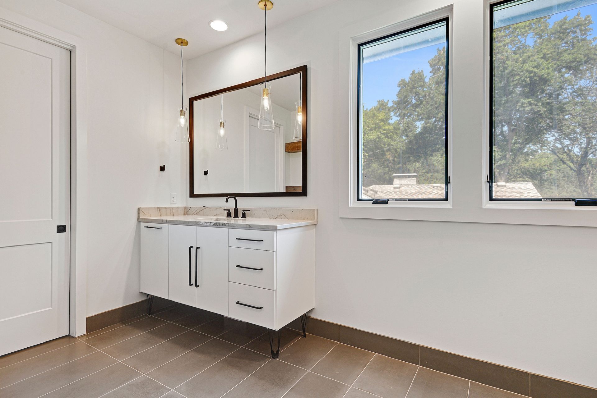 A bathroom with two sinks , a mirror and two windows.