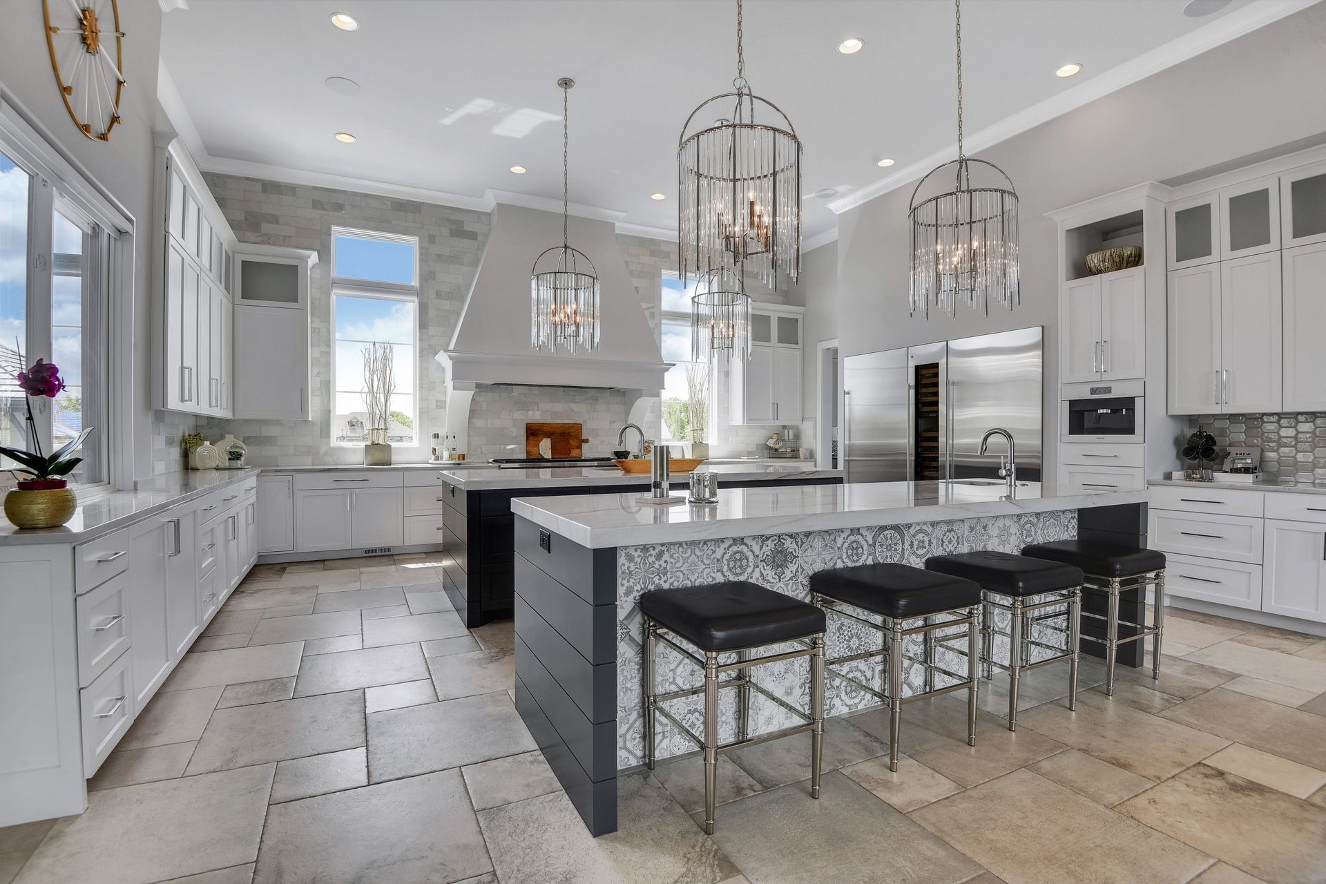 A large kitchen with white cabinets , stainless steel appliances , and a large island.