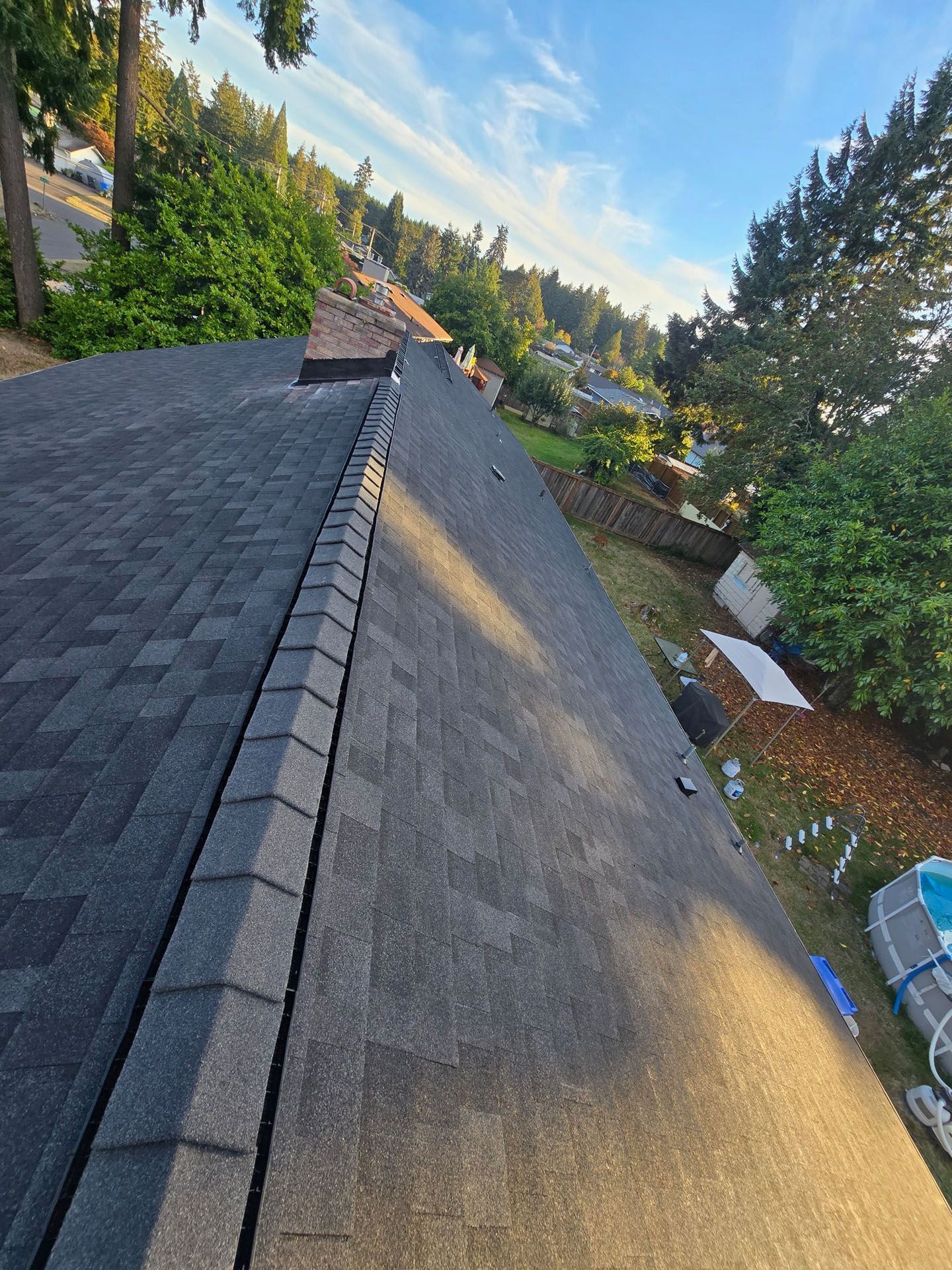 Red terracotta tile roof with a central ridge under sunlight.