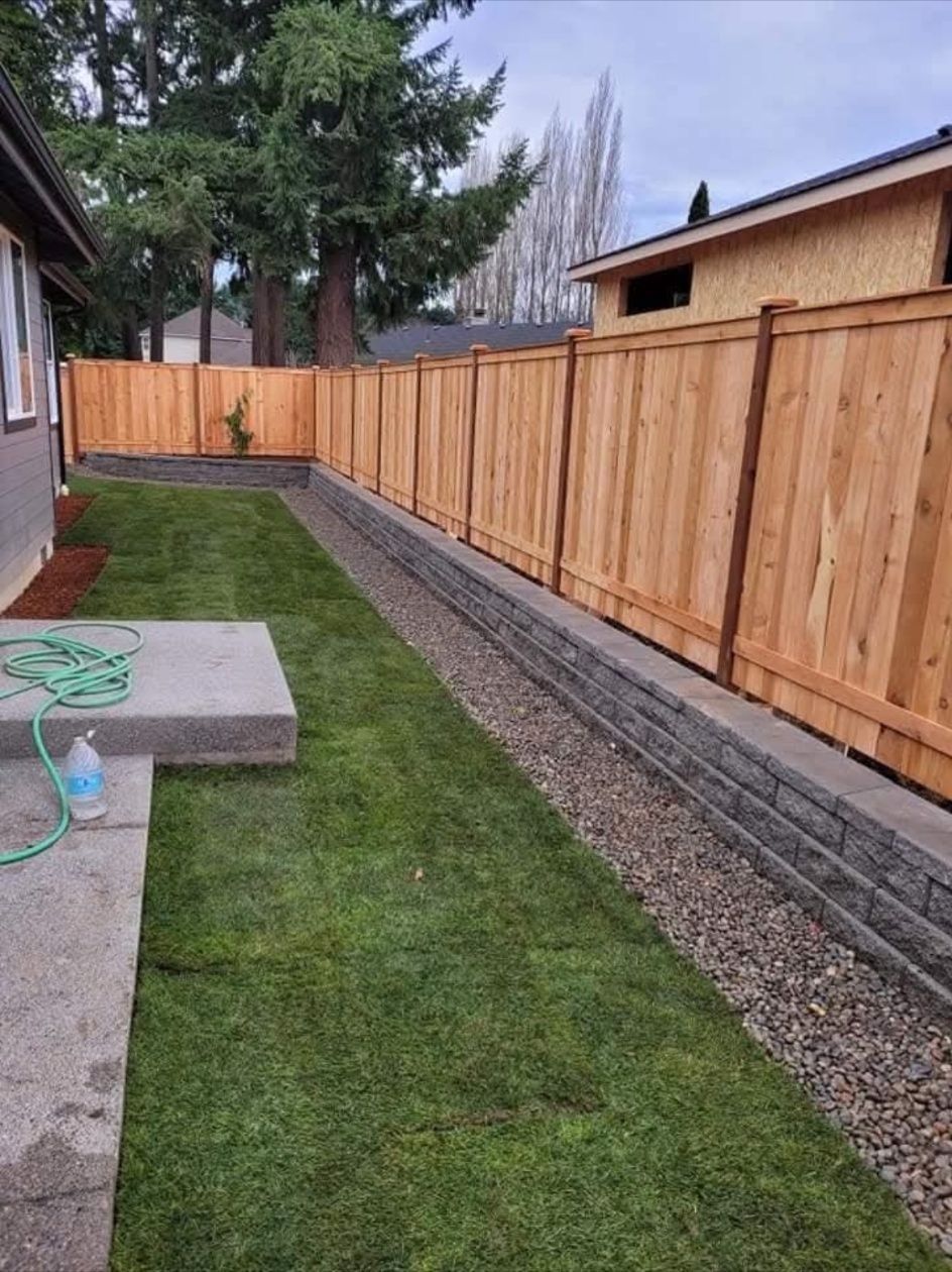 Narrow backyard with new wooden fence, grass lawn, gravel border, and concrete patio slab