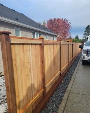 Wooden privacy fence beside a sidewalk and parked car along a residential driveway