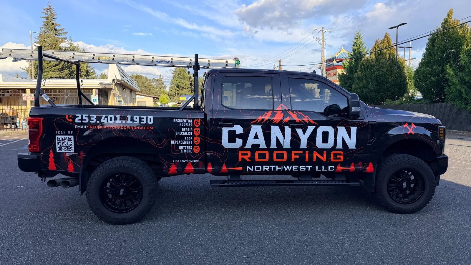 Black pickup truck with CANYON ROOFING branding parked outdoors on a sunny day