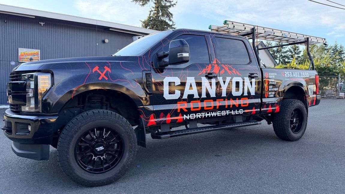Black Canyon Roofing Northwest heavy-duty pickup truck with large orange-and-white branding, parked outdoors.