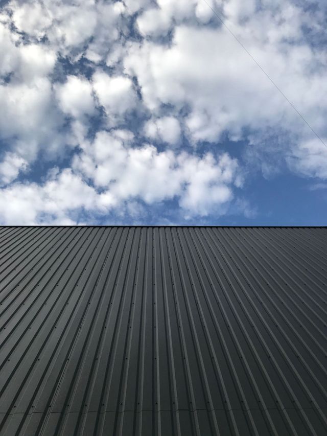 Cloudy sky above a dark corrugated metal roof