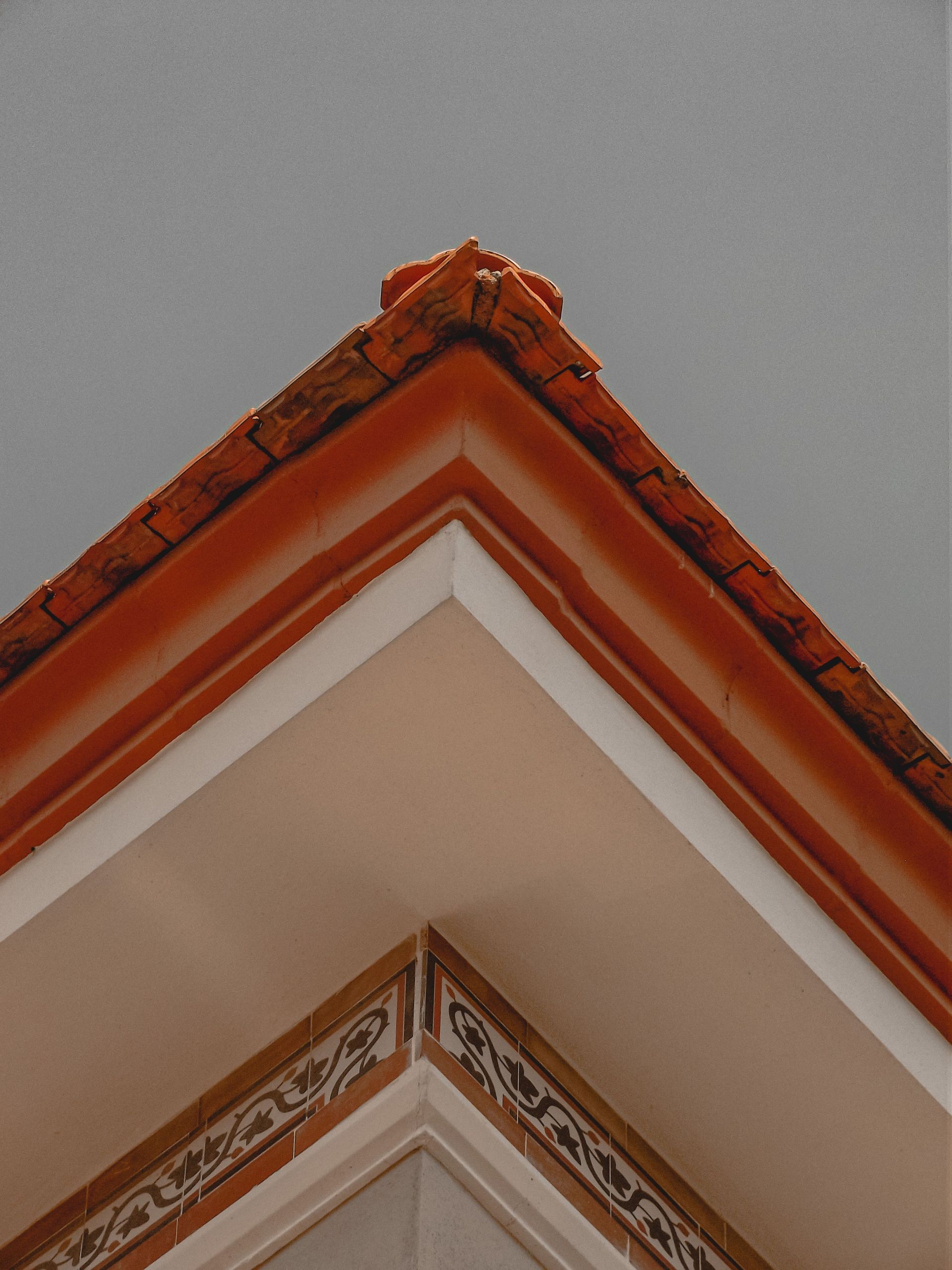 Corner of a cream and terracotta building roof against a gray sky