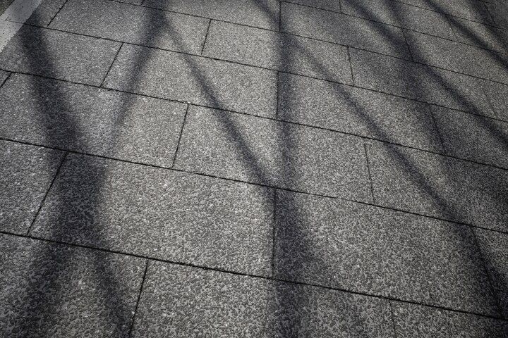 Shadow patterns on gray rooftop shingles in bright sunlight