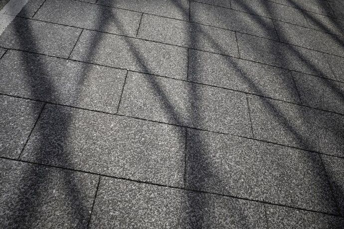 Shadow patterns on gray rooftop shingles in bright sunlight