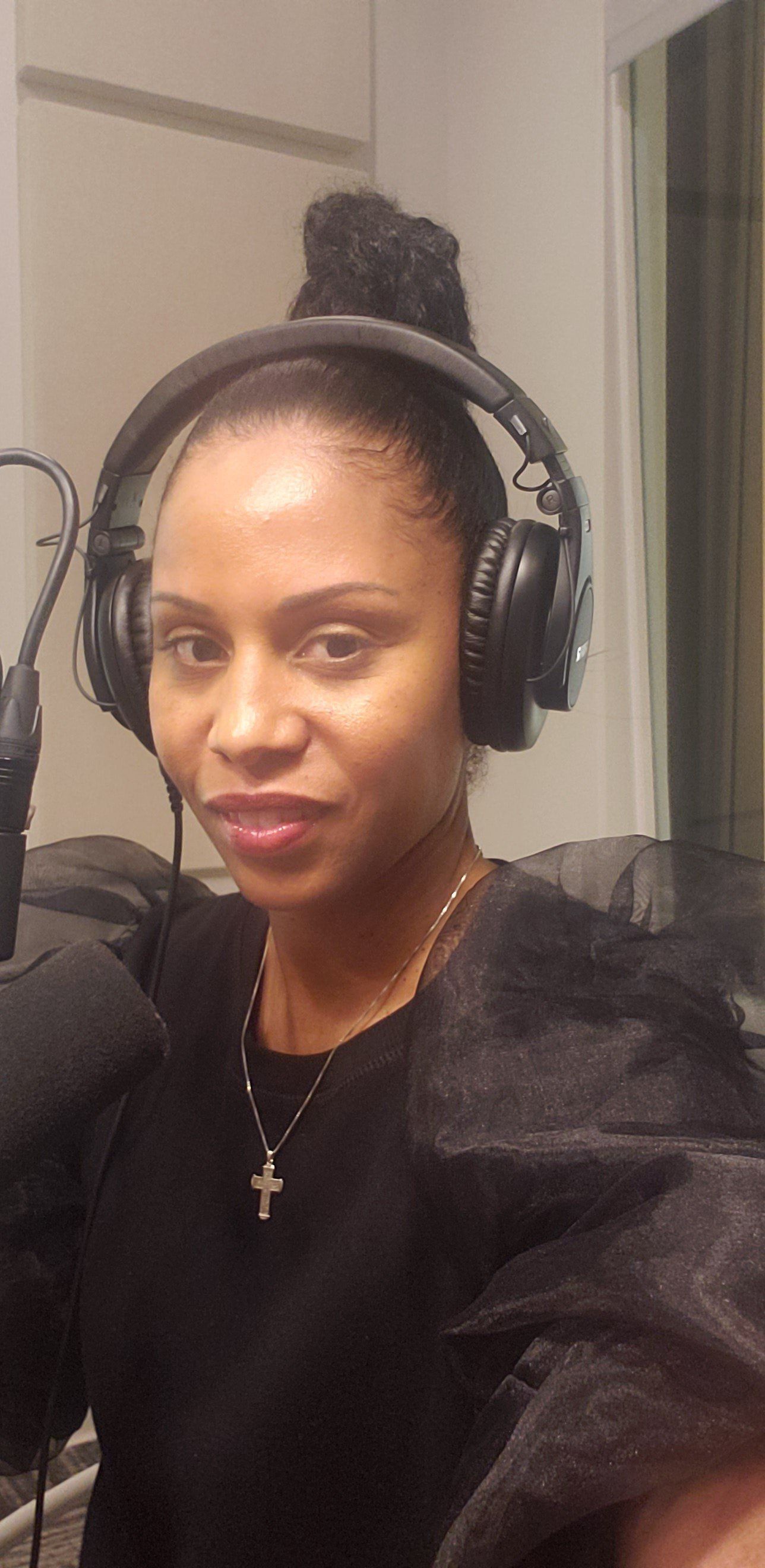 Woman wearing headphones in a recording studio, looking at the camera.
