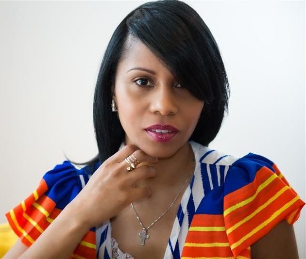 Woman with black hair, wearing a patterned top, looking directly at the viewer.