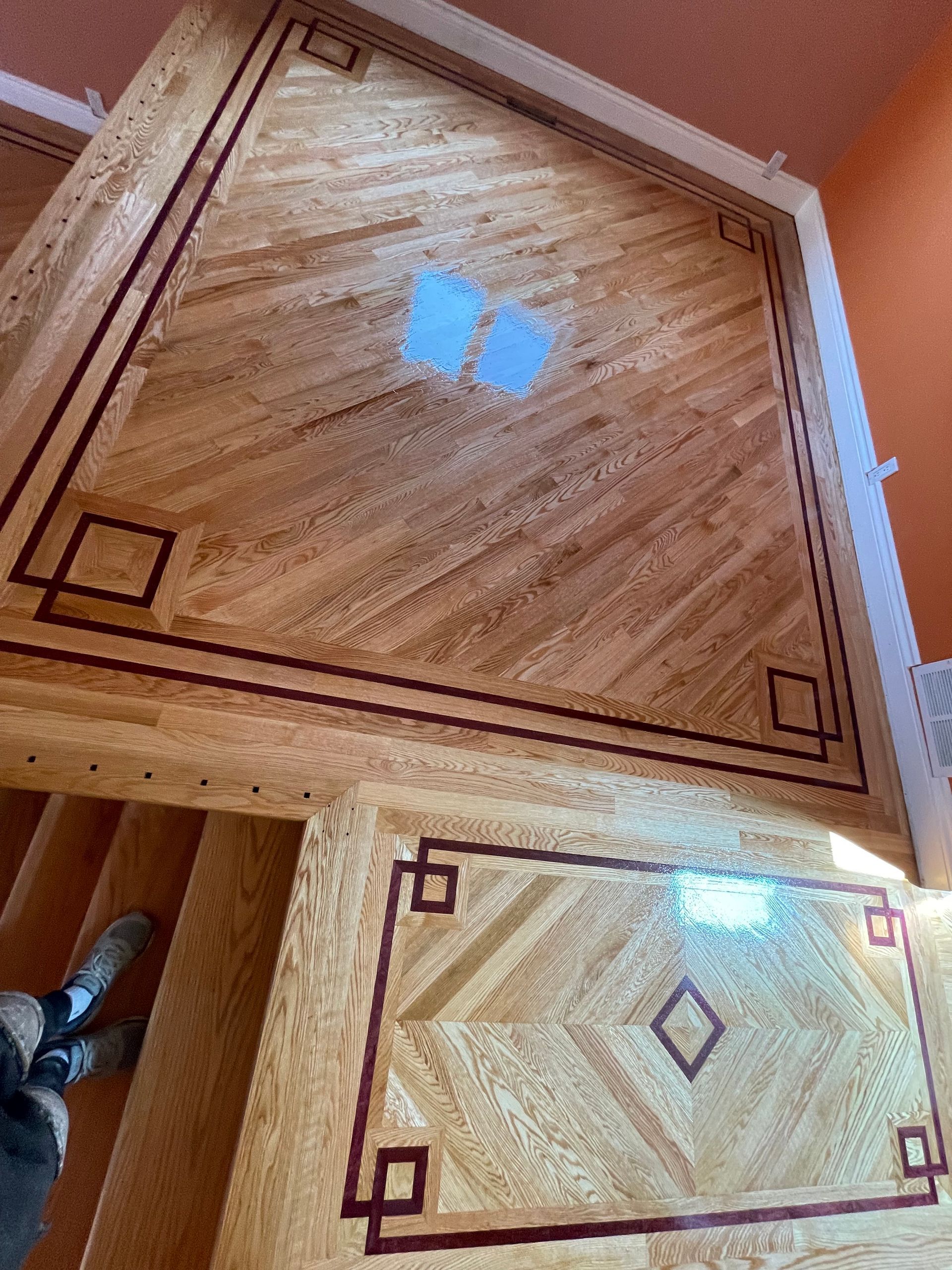 a wooden floor with a geometric pattern and stairs in the background .