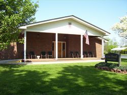 A brick building with a covered porch and a sign reading