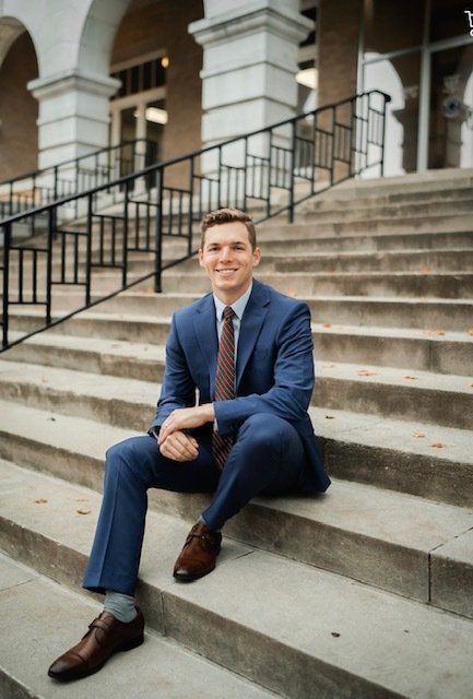 A man in a suit and tie is sitting on a set of stairs.