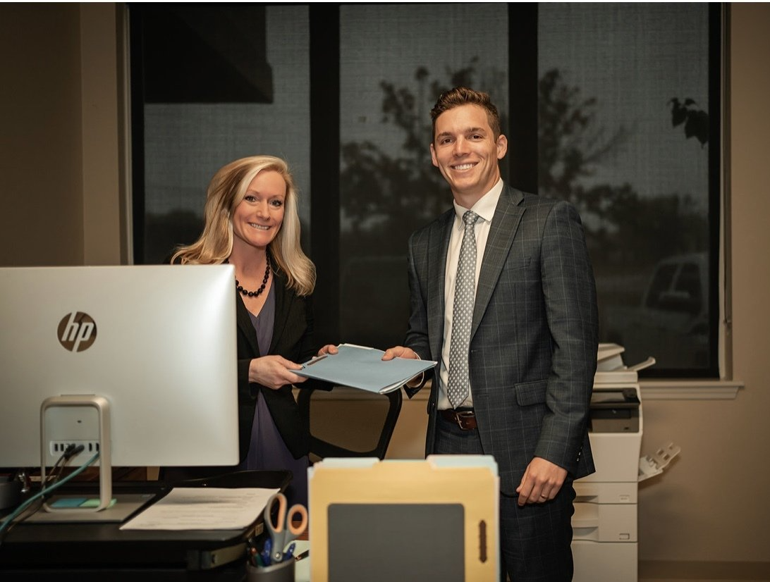 A man and a woman are standing next to each other in front of a computer.