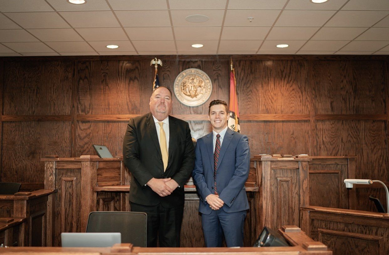 Two men in suits are standing next to each other in a courtroom.