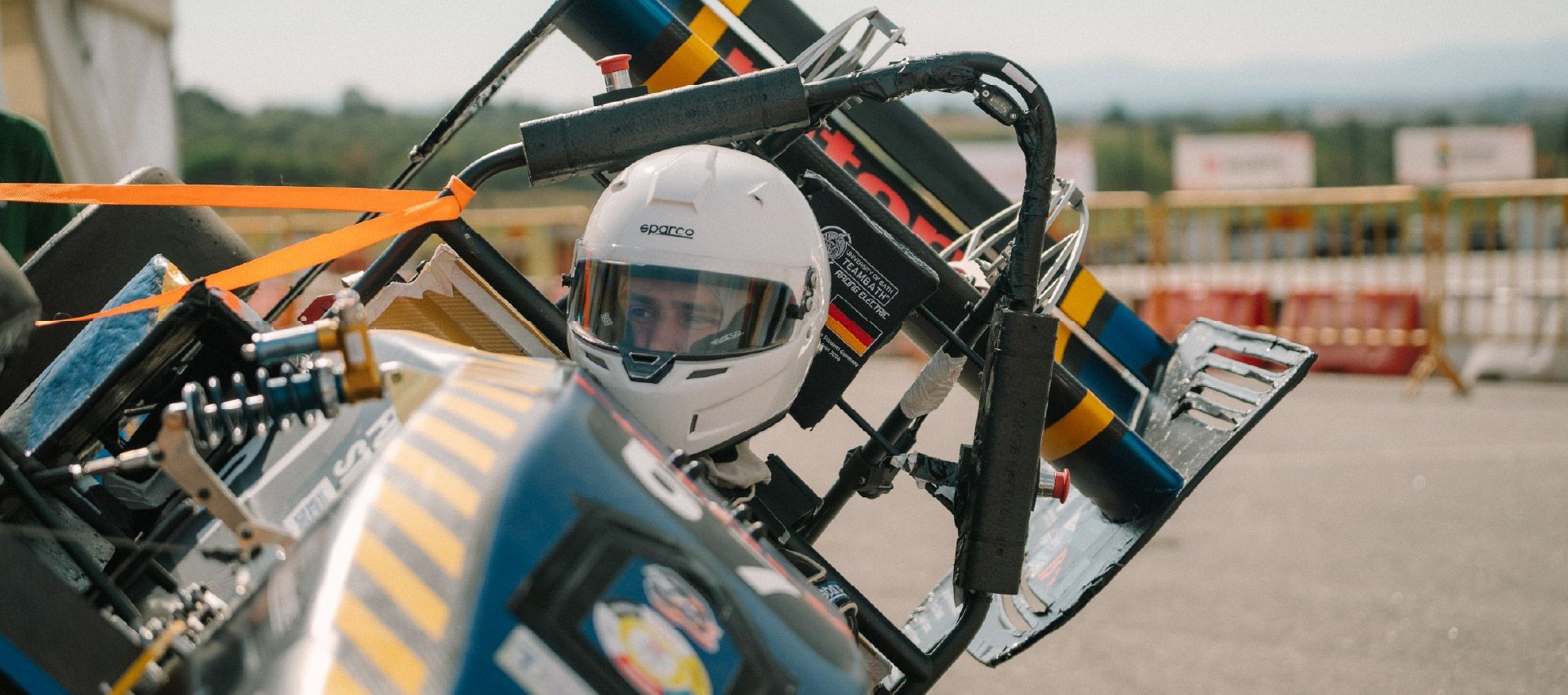 Team Bath Formula Student Race Car testing with driver wearing a white helmet.