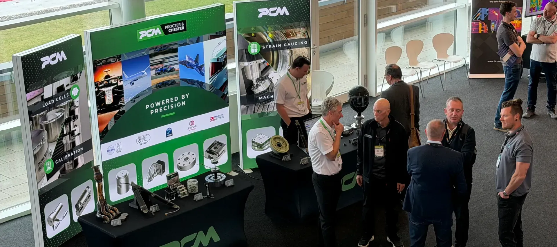 Team members of PCM talking with other load cell and strain gauging experts at their stand.