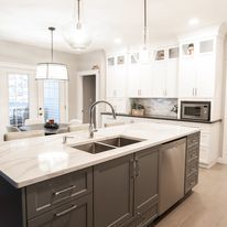 Modern kitchen with grey island, white countertops, and cabinetry.