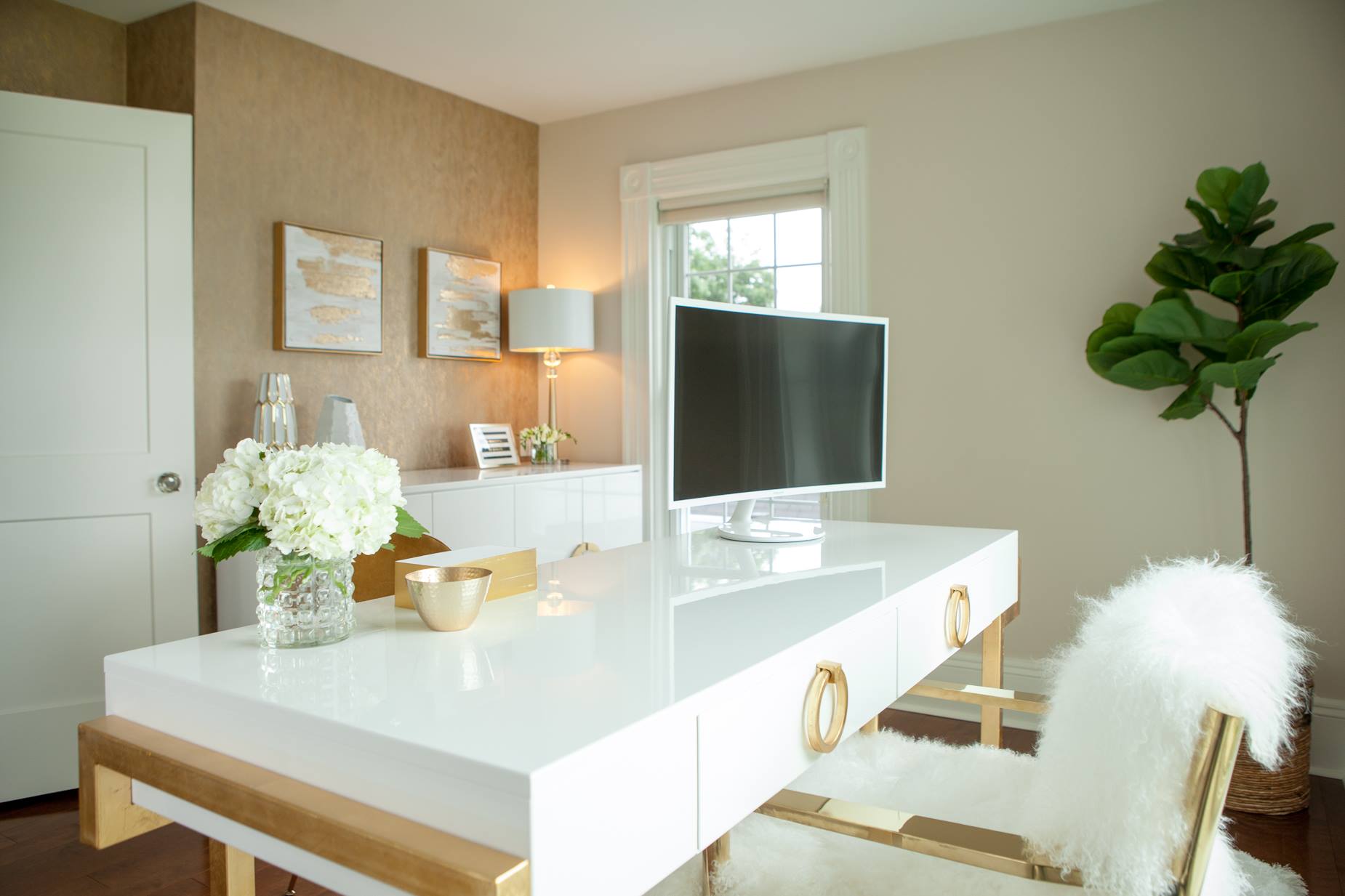 Elegant home office with white desk, gold accents, and a faux fur chair.