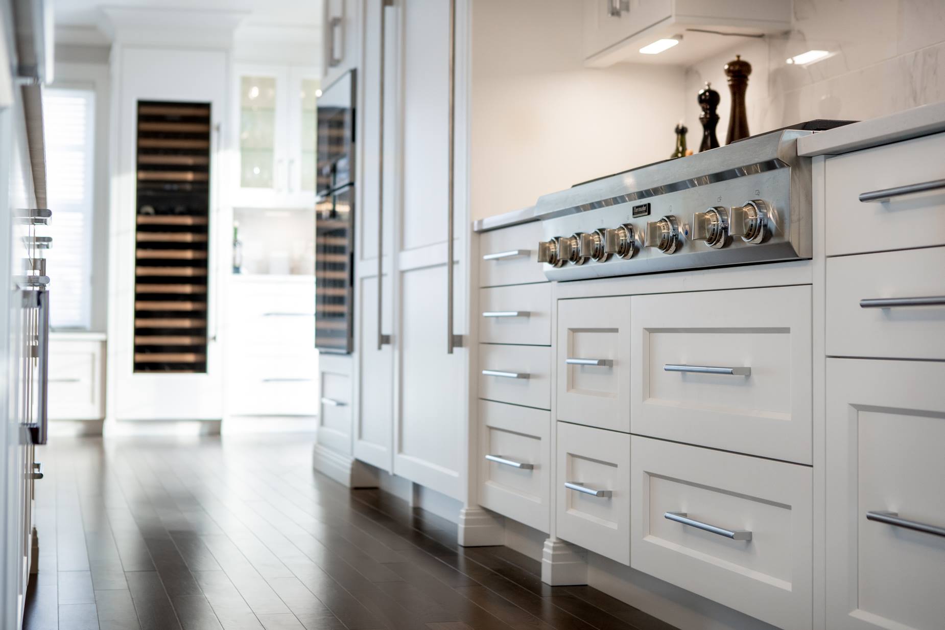 White kitchen with stainless steel appliances, hardwood floor.