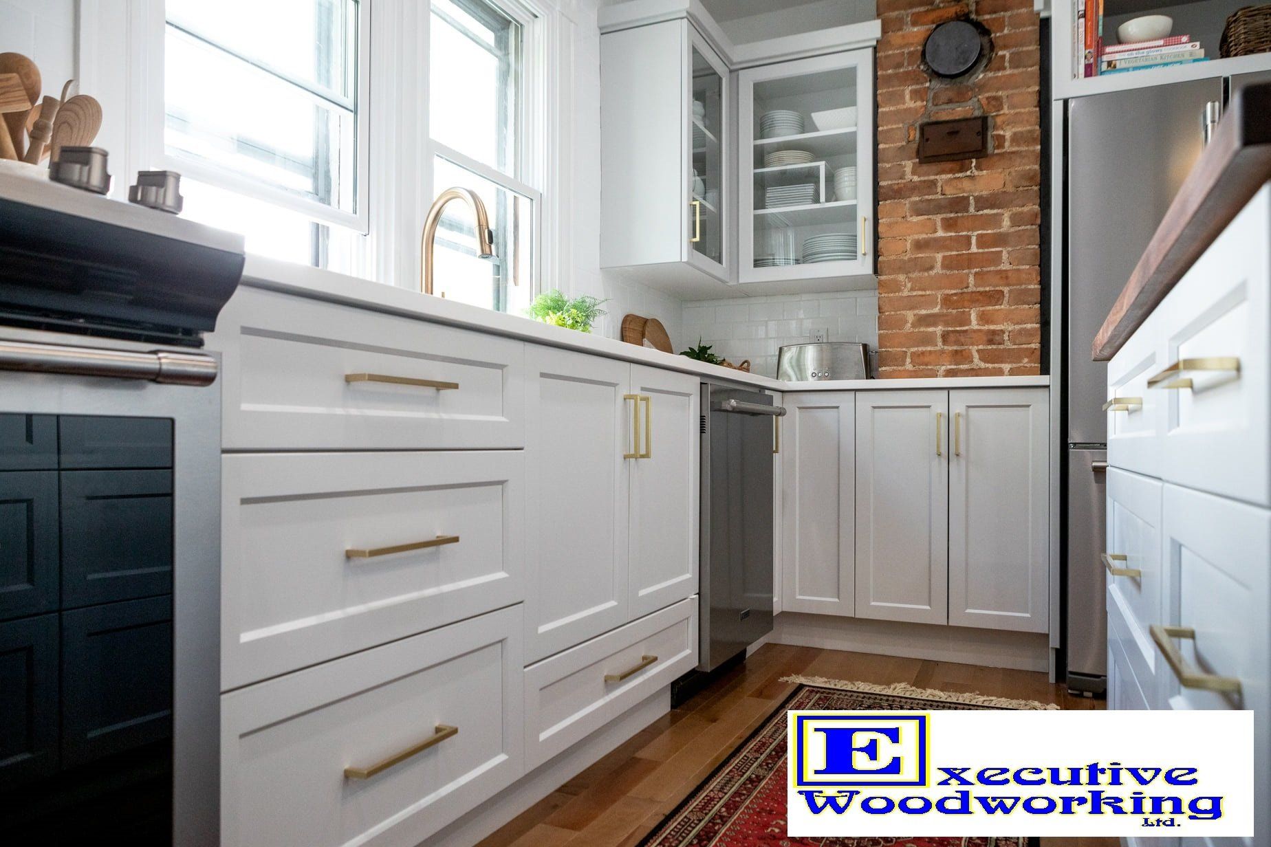 White kitchen with gold hardware, exposed brick, and a built-in dishwasher.