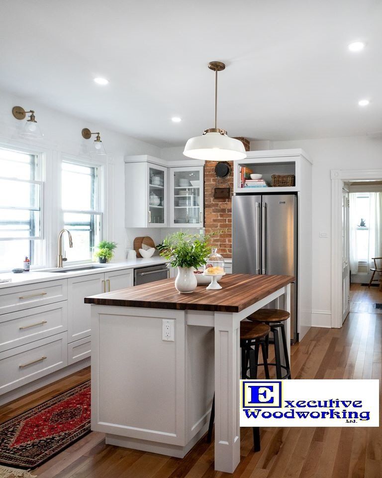 Bright white kitchen with island, wood countertops, stainless steel appliances, hardwood floors.
